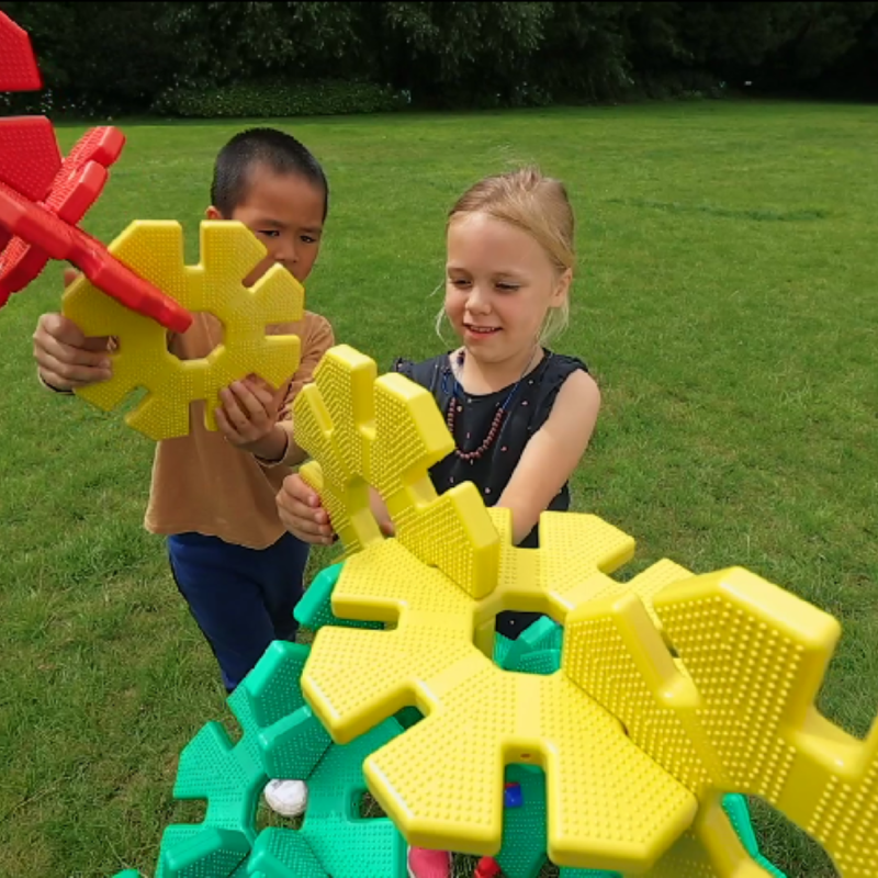 Zwei Kinder bauen ein Fantasiefahrzeug mit Octoplay-Bauscheiben im Garten. Zwei Kinder bauen ein Fantasiefahrzeug mit Octoplay-Bauscheiben im Garten.
