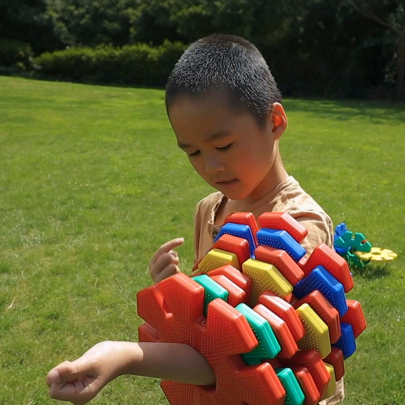 A young boy playing on the grass with a colorful Giant Octoplay creation made of red, yellow, blue, and green A young boy playing on the grass with a colorful Giant Octoplay creation made of red, yellow, blue, and green